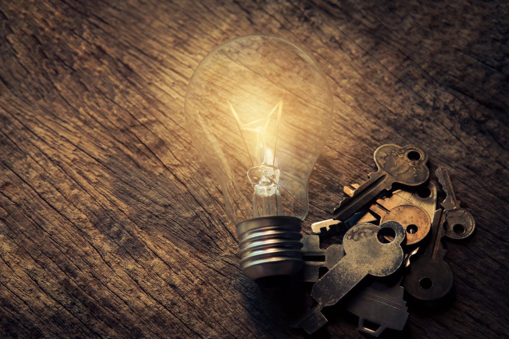 an old-fashioned lightbulb on a wooden table next to a keyring